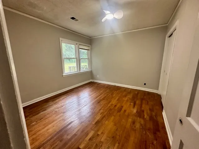a view of an empty room with wooden floor and a window