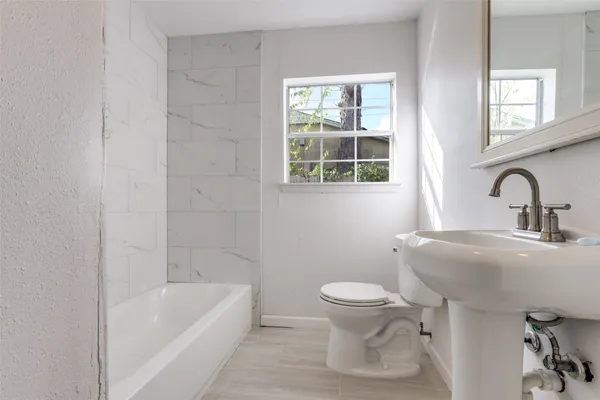 an empty room with wooden floor chandelier and windows