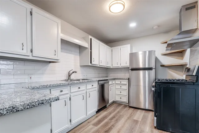 a kitchen with stainless steel appliances granite countertop a refrigerator and a stove top oven