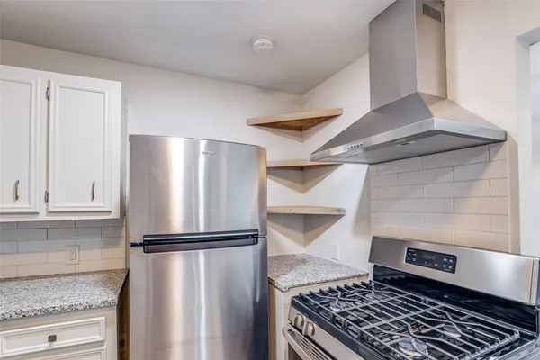 a kitchen with granite countertop white cabinets and stainless steel appliances