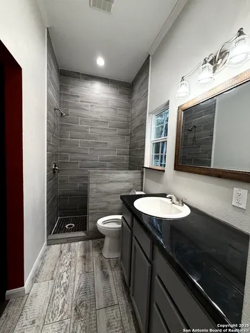 a bathroom with a sink a toilet a mirror and shower