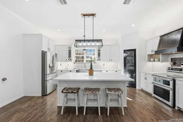 a kitchen with stainless steel appliances a dining table chairs stove refrigerator and microwave