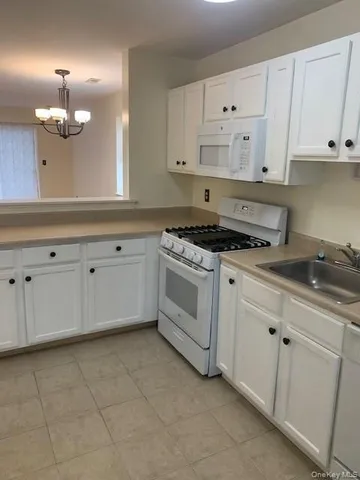 a kitchen with granite countertop white cabinets white stainless steel appliances with a sink and dishwasher
