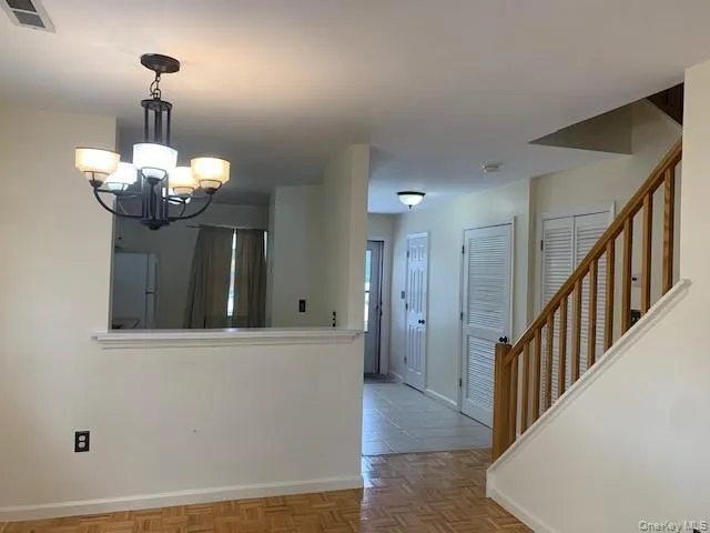 a view of a hallway with wooden floor and chandelier