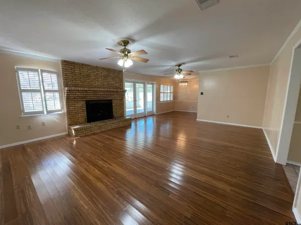 an empty room with wooden floor fireplace and windows