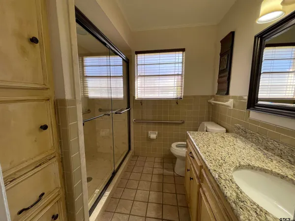a bathroom with a granite countertop toilet sink and mirror