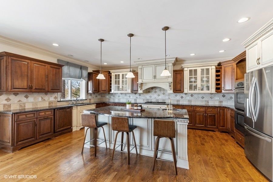 24042 Old Farm Road Manhattan, IL 60442 - Photo 8 of 32 a kitchen with stainless steel appliances granite countertop a kitchen island hardwood floor sink stove dining table and chairs