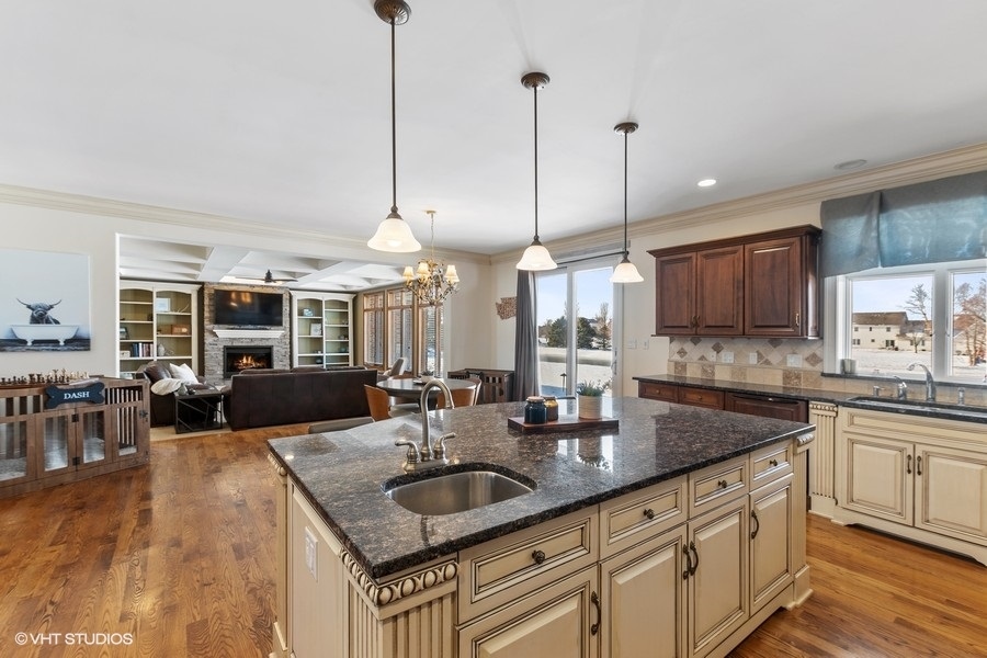 24042 Old Farm Road Manhattan, IL 60442 - Photo 10 of 32 a kitchen with kitchen island granite countertop a sink a counter top space and living room view