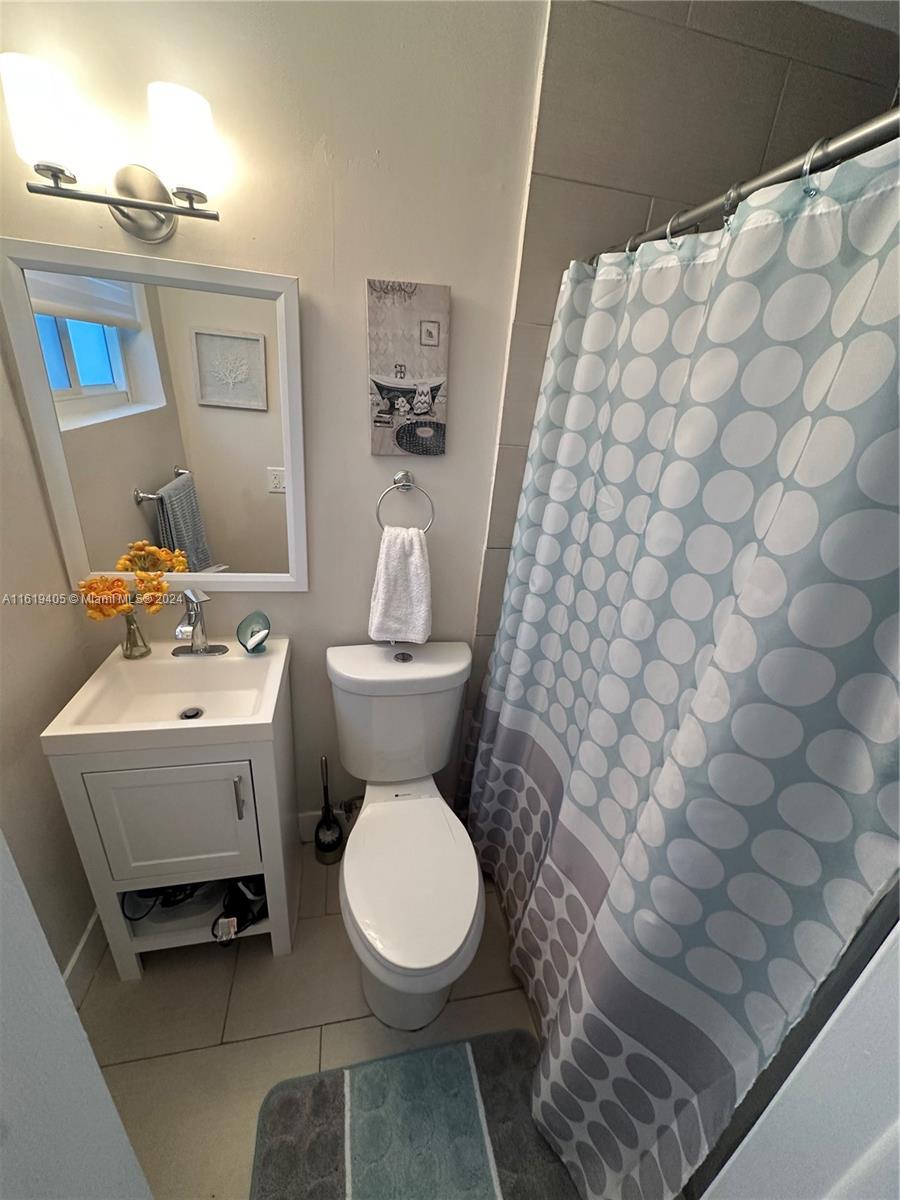 6791 Pershing Street Hollywood, FL 33024 - Photo 20 of 31 a white toilet sitting next to a white sink and vanity