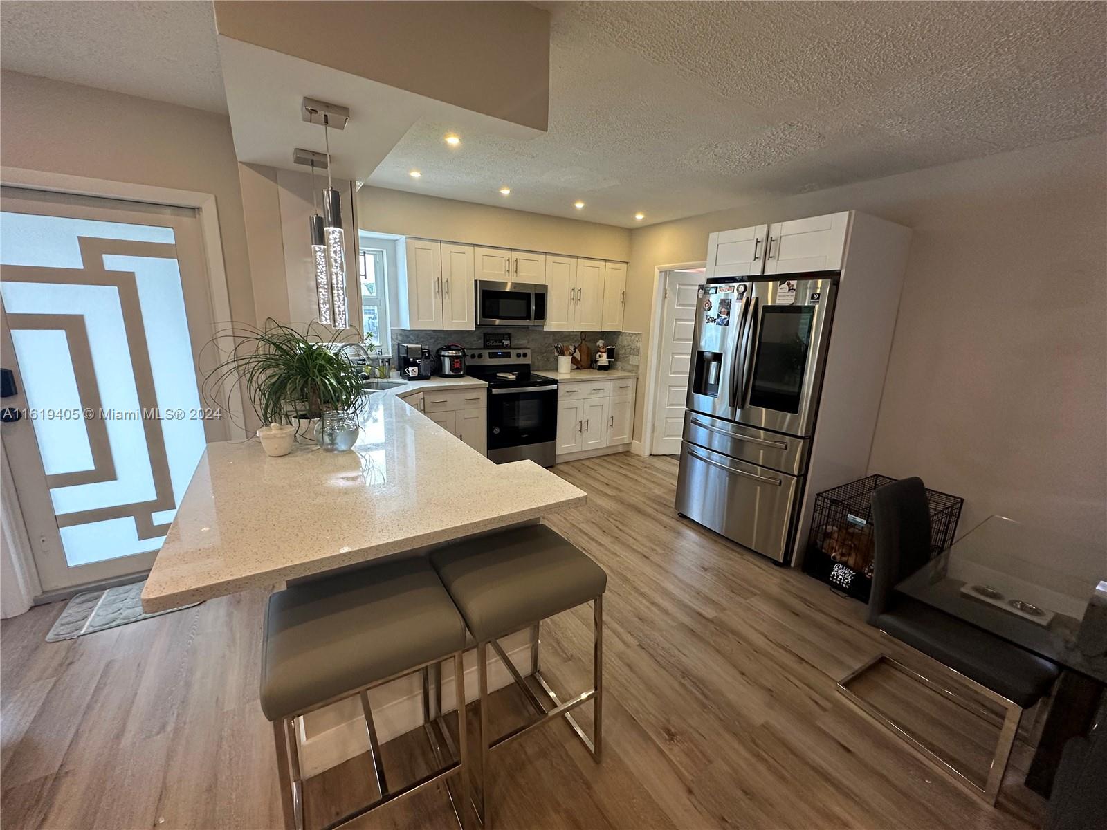 6791 Pershing Street Hollywood, FL 33024 - Photo 8 of 31 a kitchen with a table chairs refrigerator and microwave