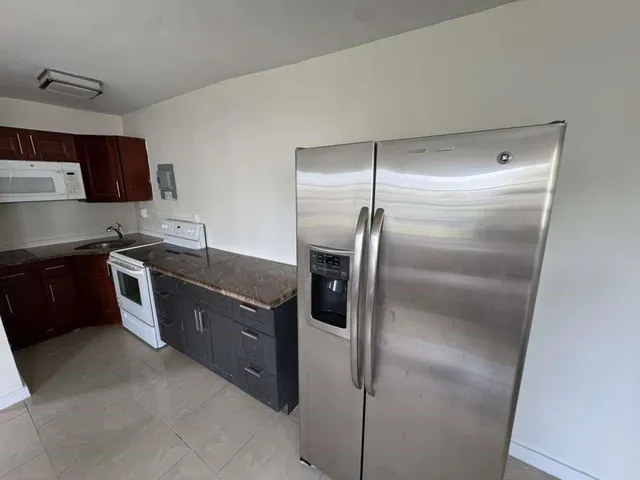 a kitchen with stainless steel appliances granite countertop a refrigerator a sink a stove and a refrigerator