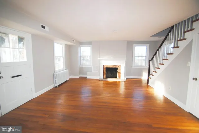 a view of empty room with wooden floor and fireplace