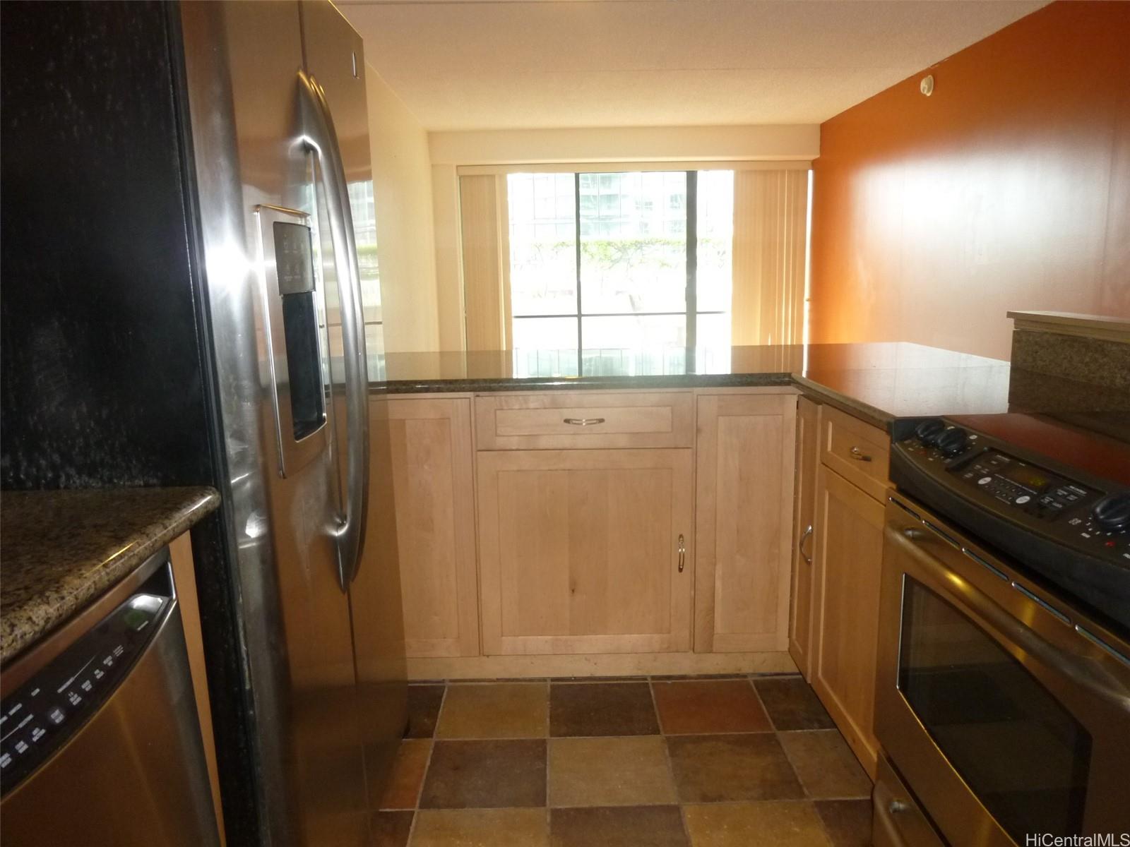 700 Richards Street, Unit 703 Honolulu, HI 96813 - Photo 9 of 12 a kitchen with a refrigerator a stove a washer dryer and white cabinets