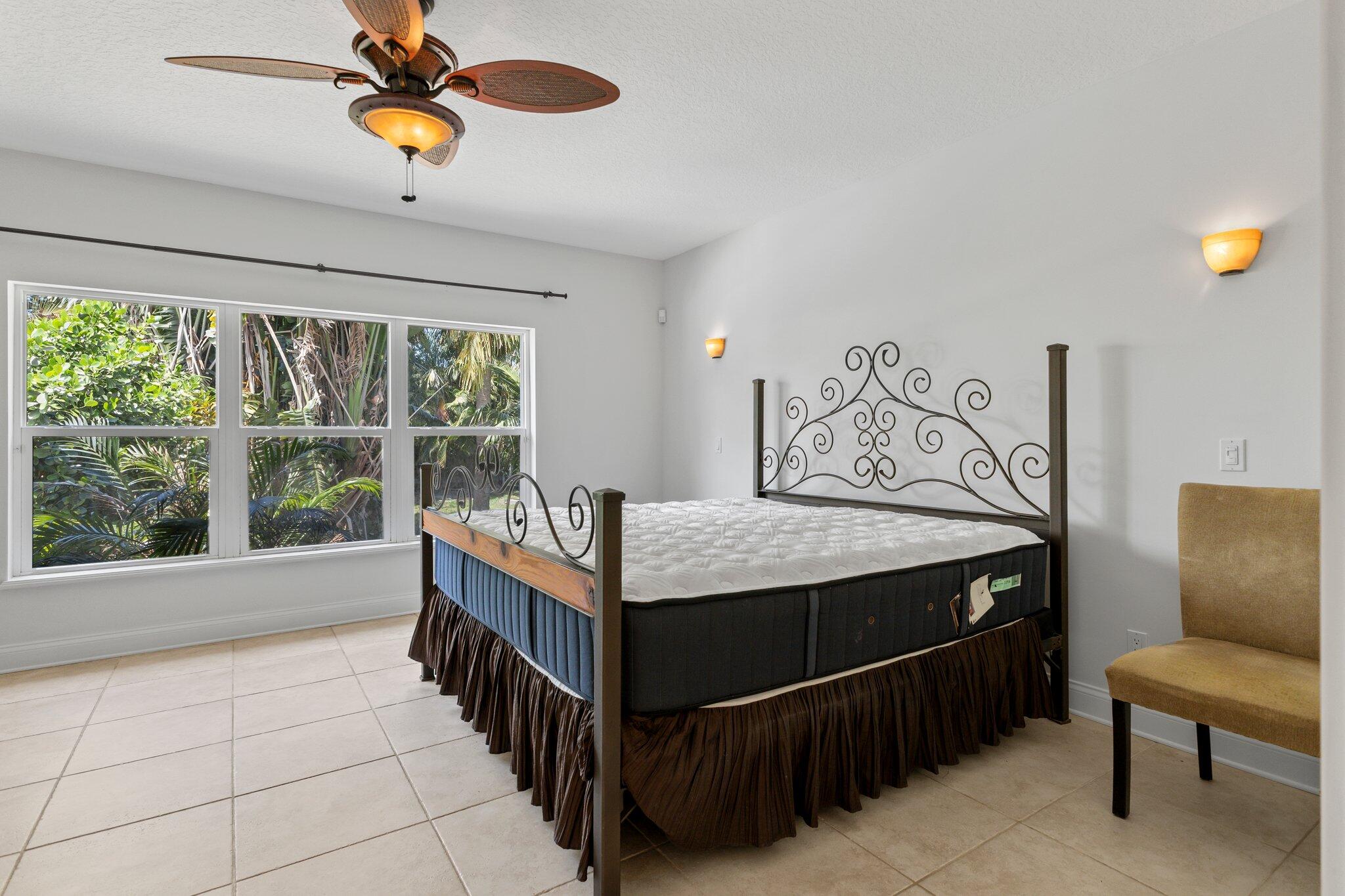 1293 Southwest Heather Terrace Stuart, FL 34997 - Photo 21 of 80 a bedroom with a bed and a chandelier