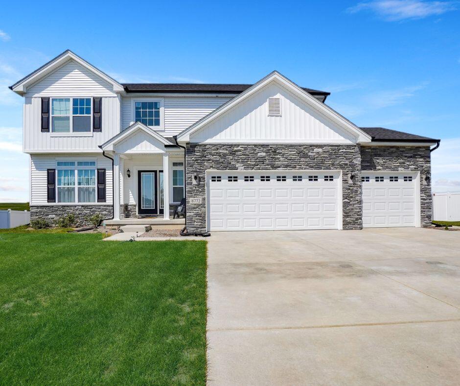 a front view of a house with yard and parking