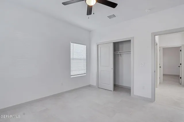 an empty room with a ceiling fan and window