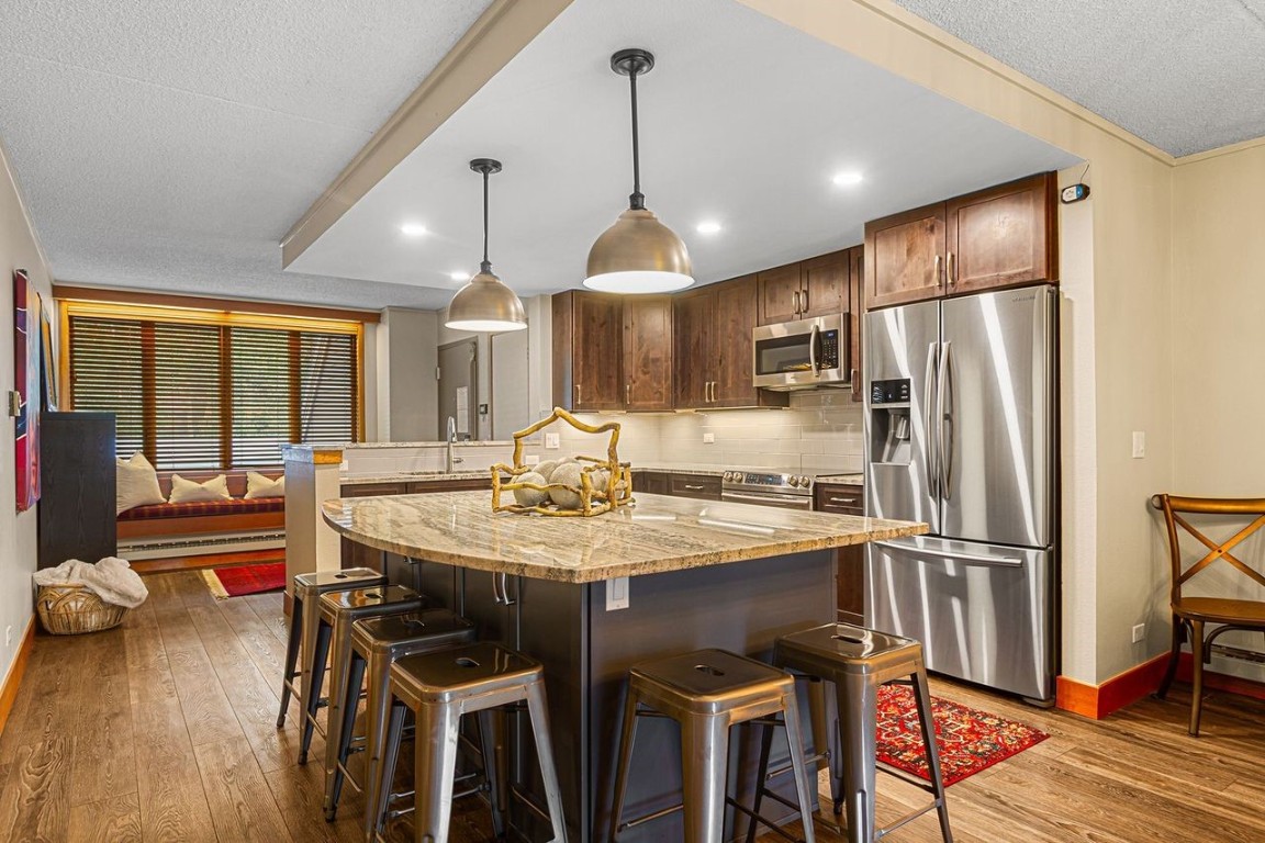 21650 Highway 6, Unit 2110 Keystone, CO 80435 - Photo 9 of 26 a kitchen with stainless steel appliances granite countertop a dining table chairs refrigerator and sink