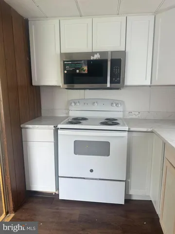 a kitchen with stainless steel appliances granite countertop white cabinets a stove a microwave and a refrigerator