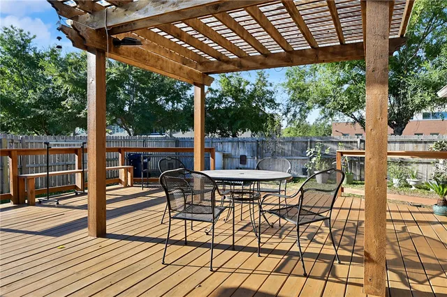 a view of patio with table and chairs under an umbrella with a barbeque