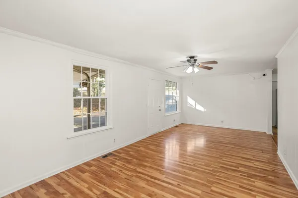 a view of an empty room with wooden floor and a window