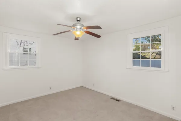 an empty room with a window and ceiling fan