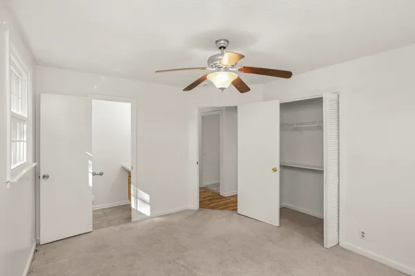 an empty room with closet and a ceiling fan