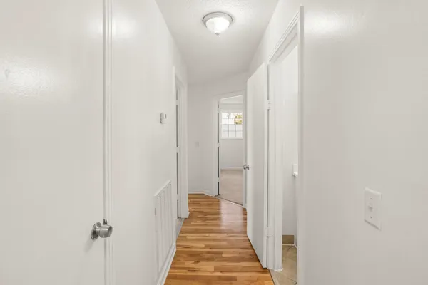 a view of a hallway with wooden floor and a bathroom