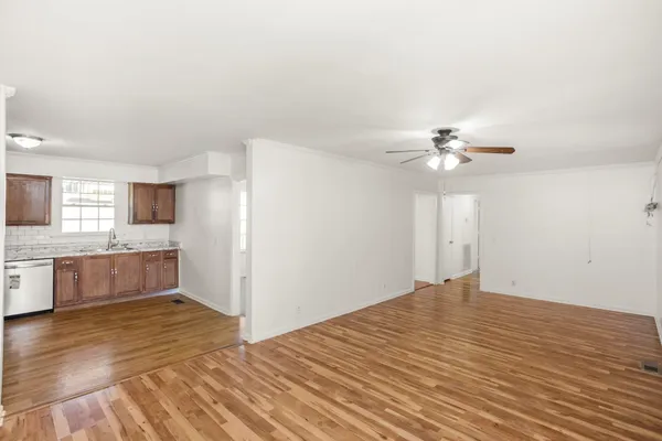 a view of kitchen and empty room with wooden floor