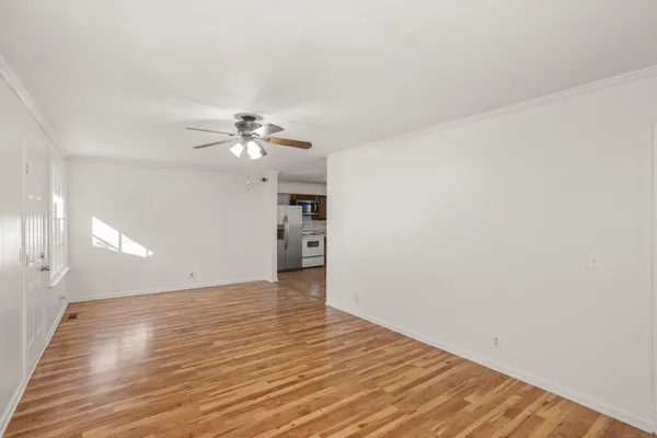 a view of a room with wooden floor and a ceiling fan