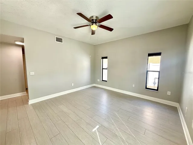 an empty room with wooden floor and windows