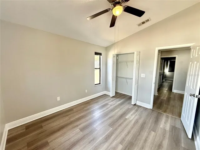 an empty room with a hardwood and ceiling fan