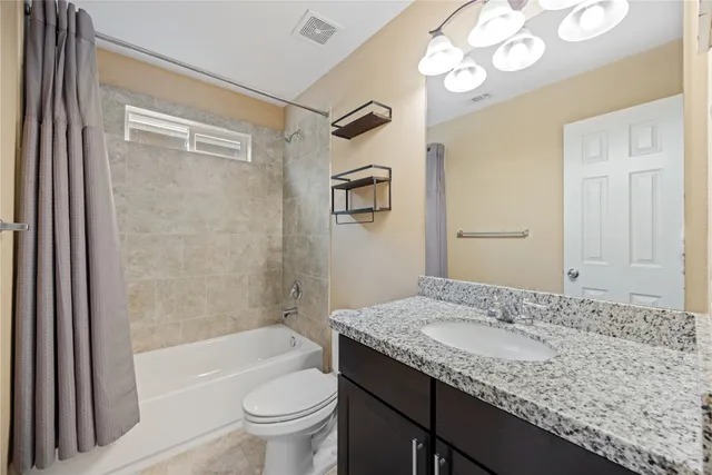 a bathroom with a granite countertop sink a toilet and shower