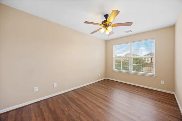 a view of an empty room with window and wooden floor