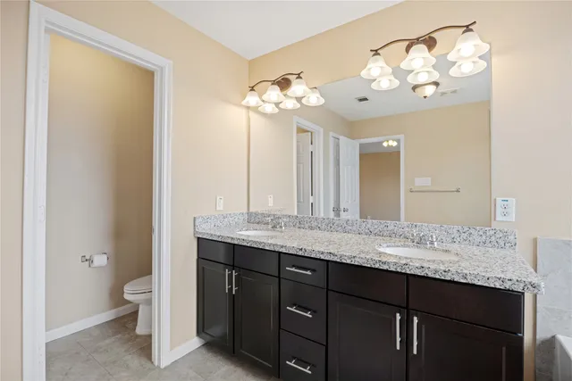 a bathroom with a granite countertop sink a large mirror and a toilet