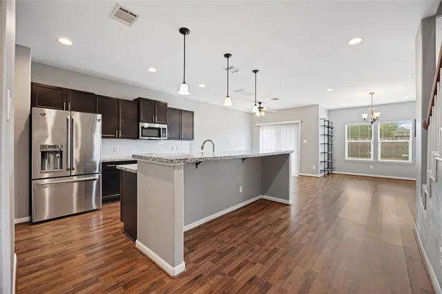 a kitchen with stainless steel appliances granite countertop a refrigerator a oven a kitchen island a sink and a refrigerator