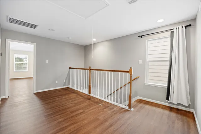 a view of a hallway with wooden floor and windows