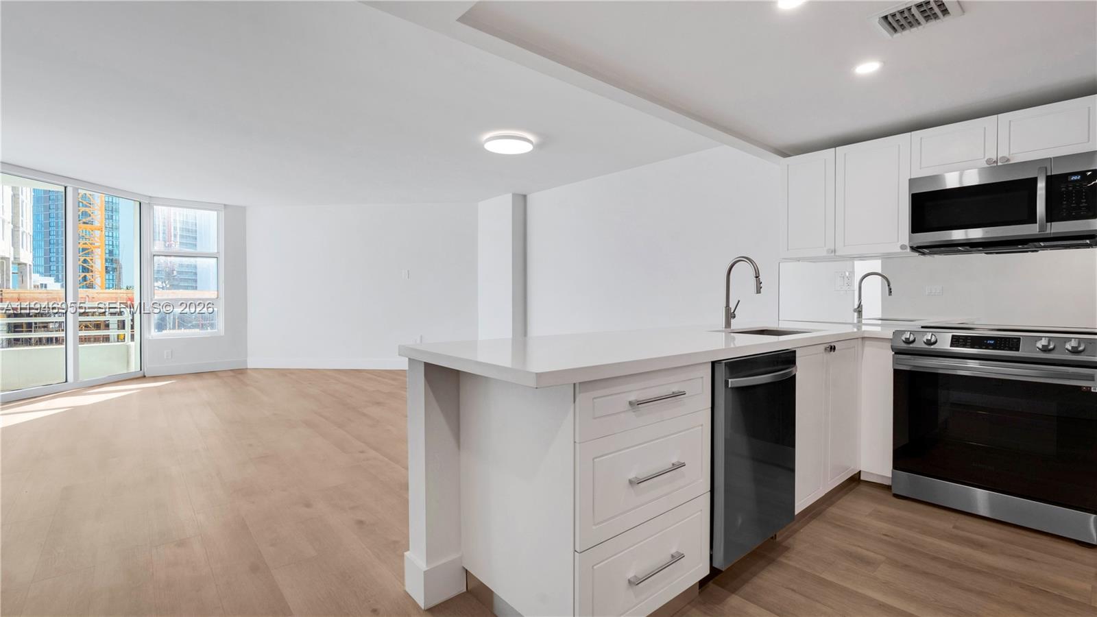555 Northeast 34th Street, Unit 1509 Miami, FL 33137 - Photo 7 of 32 a kitchen with stainless steel appliances a stove a microwave and white cabinets