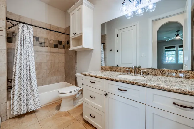 a bathroom with a granite countertop sink a toilet a mirror a vanity and shower