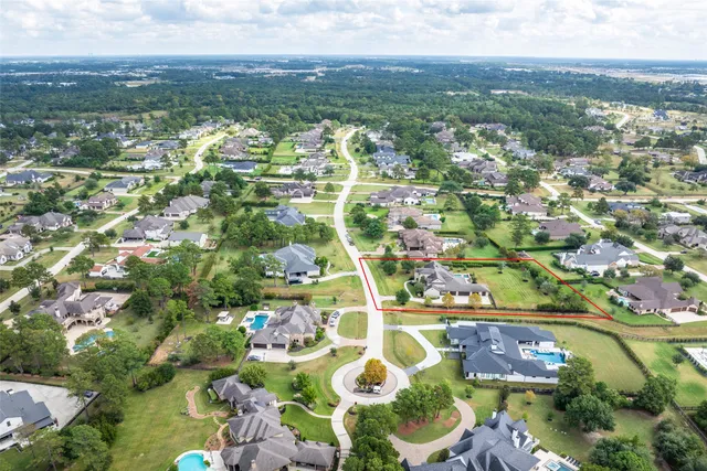 an aerial view of residential houses with outdoor space and trees