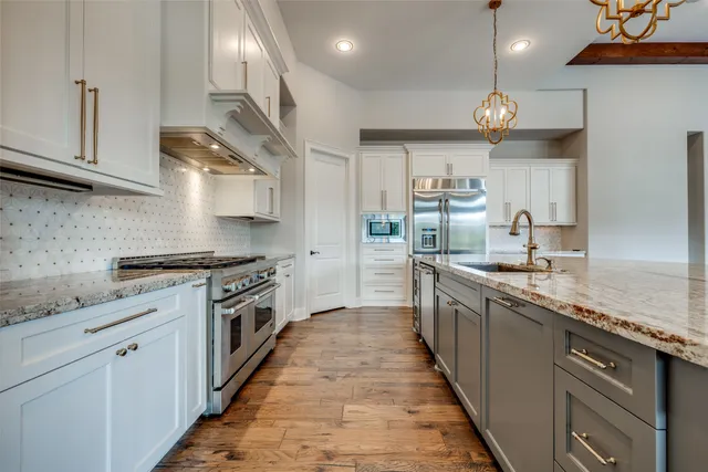 a large kitchen with stainless steel appliances granite countertop a lot of counter space and wooden floor