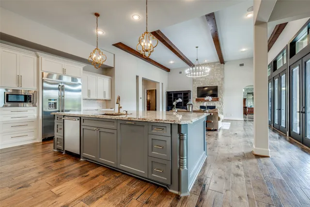 a large kitchen with stainless steel appliances kitchen island granite countertop a large counter top and wooden floors