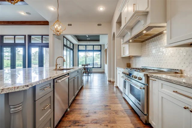 a large kitchen with stainless steel appliances granite countertop a lot of counter space and wooden floors