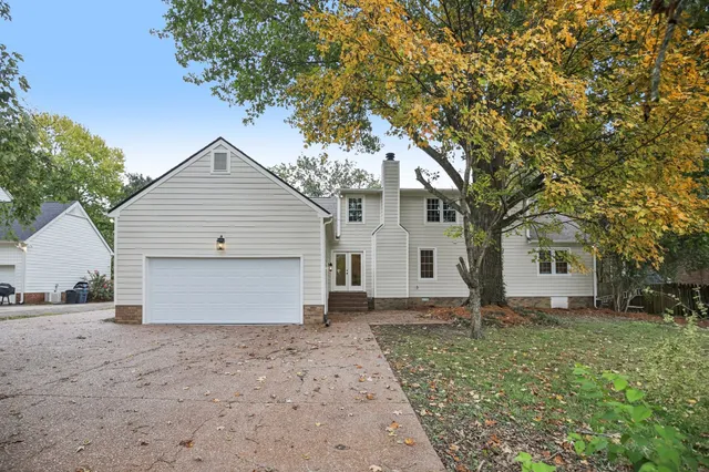a view of a house with a yard and large tree