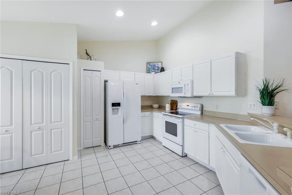 9331 Spring Run Boulevard, Unit 3003 Estero, FL 34135 - Photo 10 of 47 a kitchen with white cabinets a sink stove and refrigerator