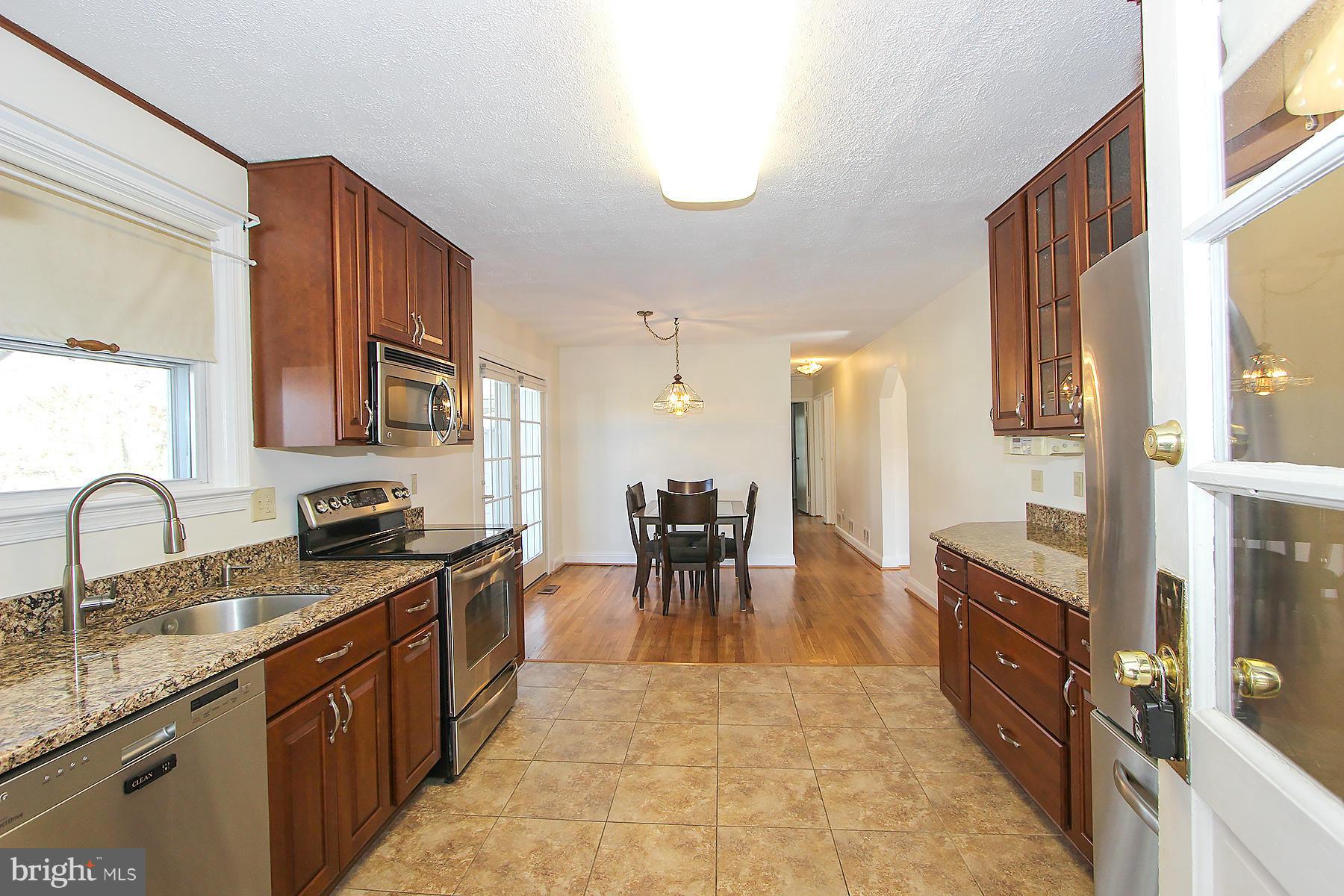 20820 Slidell Road Boyds, MD 20841 - Photo 10 of 29 a kitchen with granite countertop a stove top oven a sink a dining table and chairs