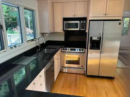 a kitchen with granite countertop a sink cabinets and stainless steel appliances