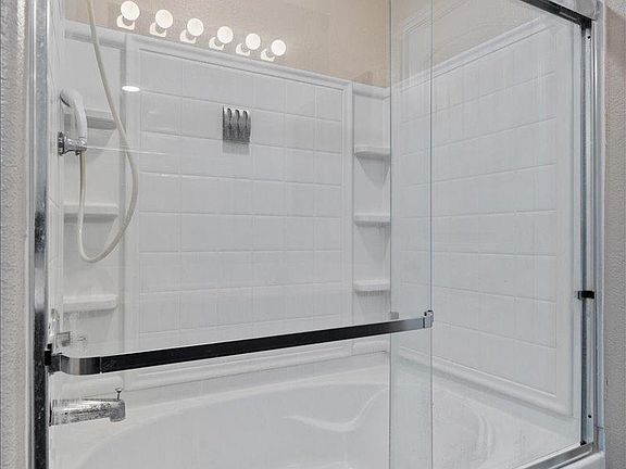 904 Lonesome Lilly Way Pflugerville, TX 78660 - Photo 24 of 34 Bathroom featuring a shower and tub combination with a clear glass enclosure and white tiled walls