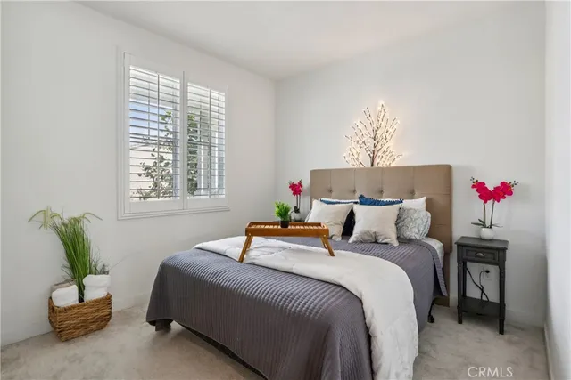 a bedroom with a bed a couch and potted plant on the table