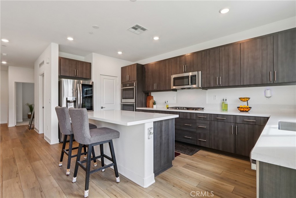2464 Yellowstone Way Rialto, CA 92377 - Photo 9 of 75 a kitchen with stainless steel appliances granite countertop a refrigerator a stove top oven a sink dishwasher and a dining table with wooden floor
