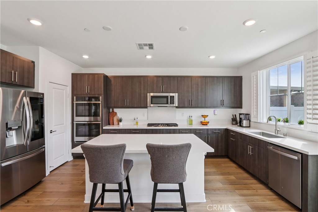 2464 Yellowstone Way Rialto, CA 92377 - Photo 10 of 75 a kitchen with stainless steel appliances a sink a stove a refrigerator cabinets and a center island